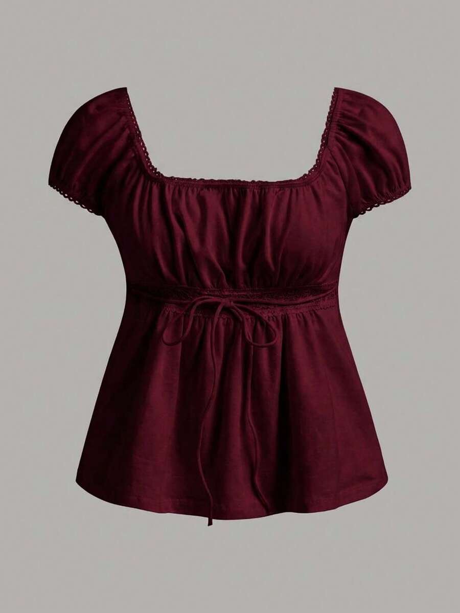 Women's black short puff sleeve top featuring a square neckline, ruched bust detail, and flared ruffle hem.