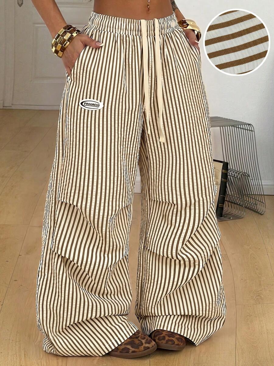 Women's black and white striped wide leg pants featuring an elastic drawstring waistband, side pockets, and a loose straight leg fit.