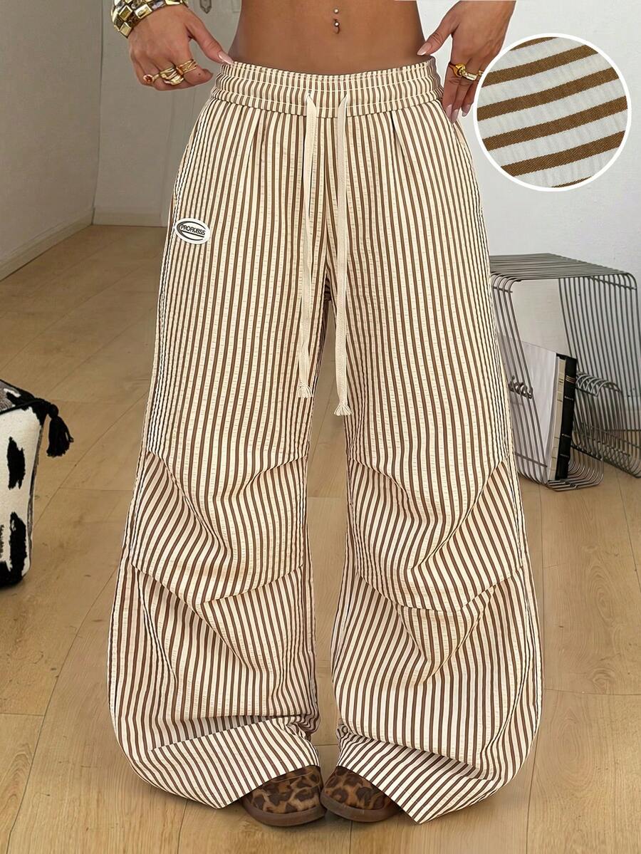 Women's black and white striped wide leg pants featuring an elastic drawstring waistband, side pockets, and a loose straight leg fit.