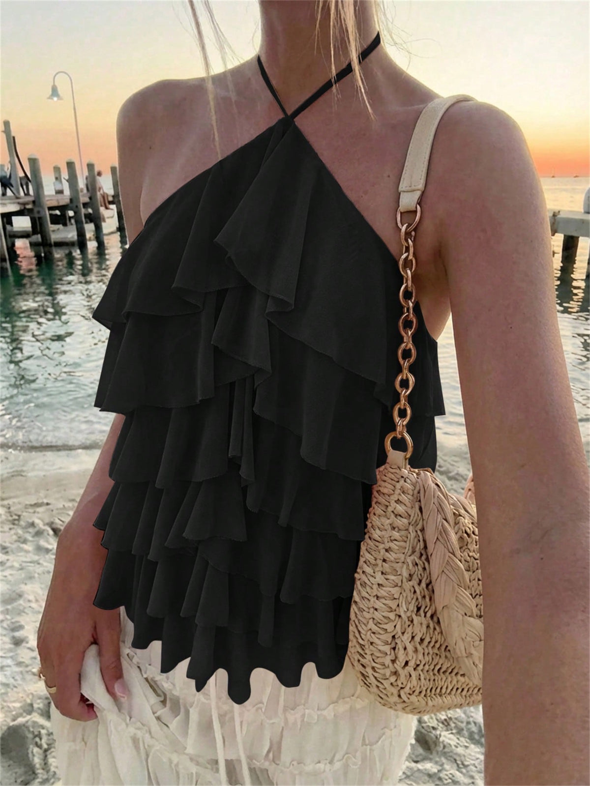 Women's sleeveless halter neck top featuring tiered ruffle layers, a backless cut, and an asymmetrical hem.