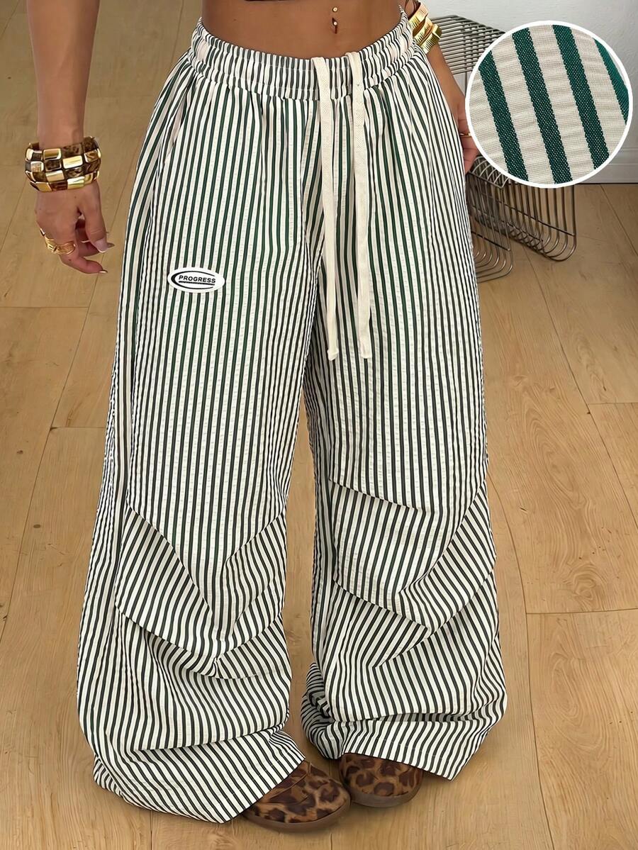 Women's black and white striped wide leg pants featuring an elastic drawstring waistband, side pockets, and a loose straight leg fit.