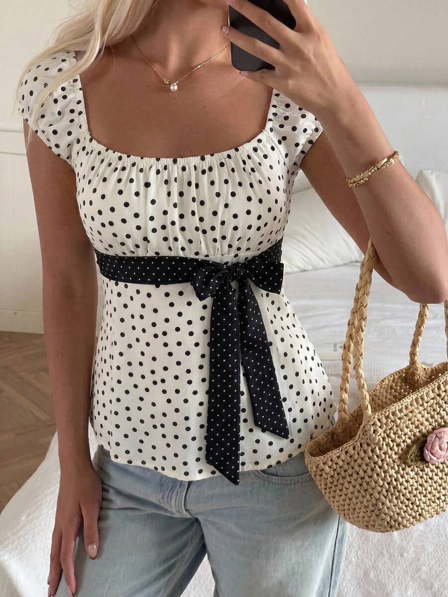 Women's short sleeve square neck polka dot top with ruched detailing, flared hem, and waist tie back.