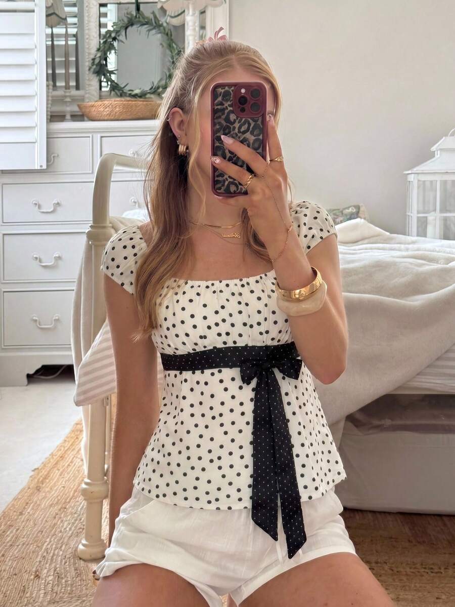 Women's short sleeve square neck polka dot top with ruched detailing, flared hem, and waist tie back.