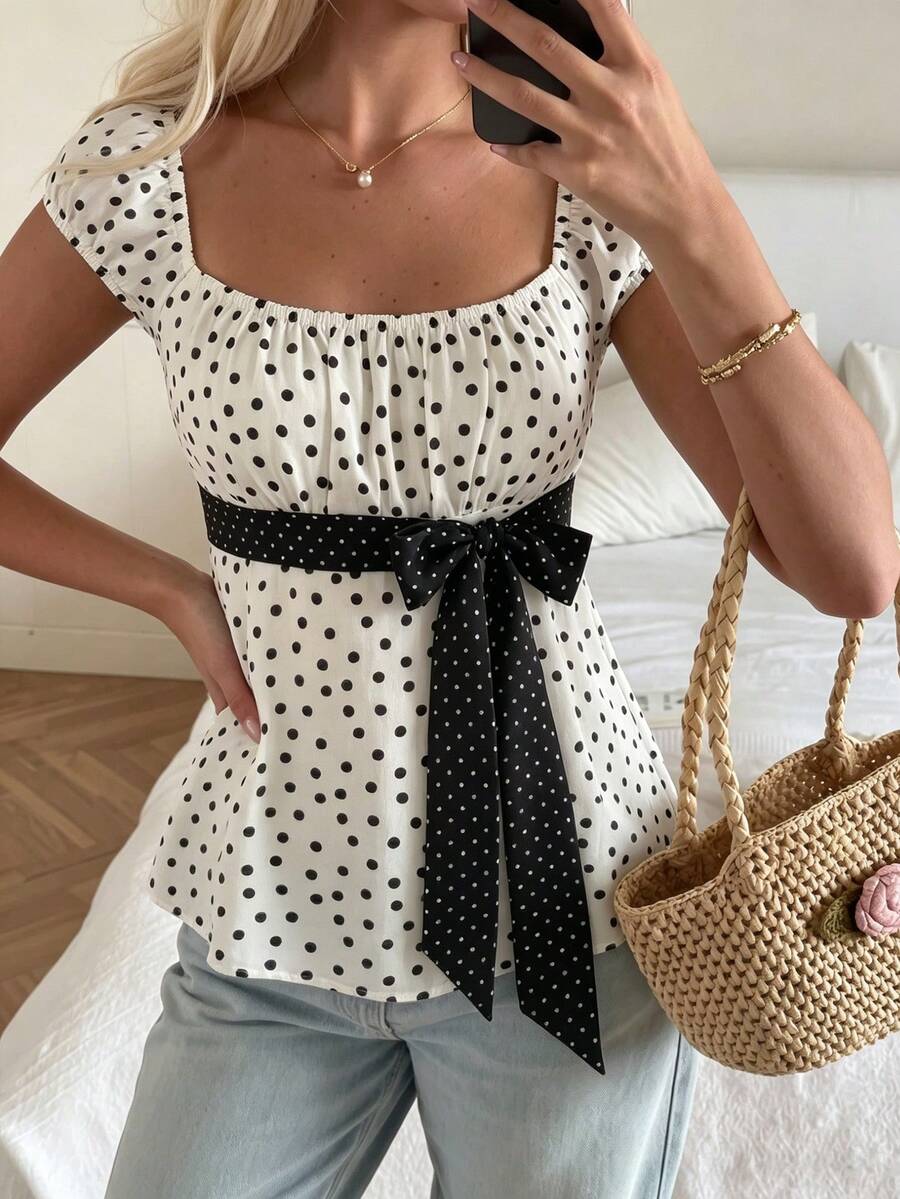Women's short sleeve square neck polka dot top with ruched detailing, flared hem, and waist tie back.