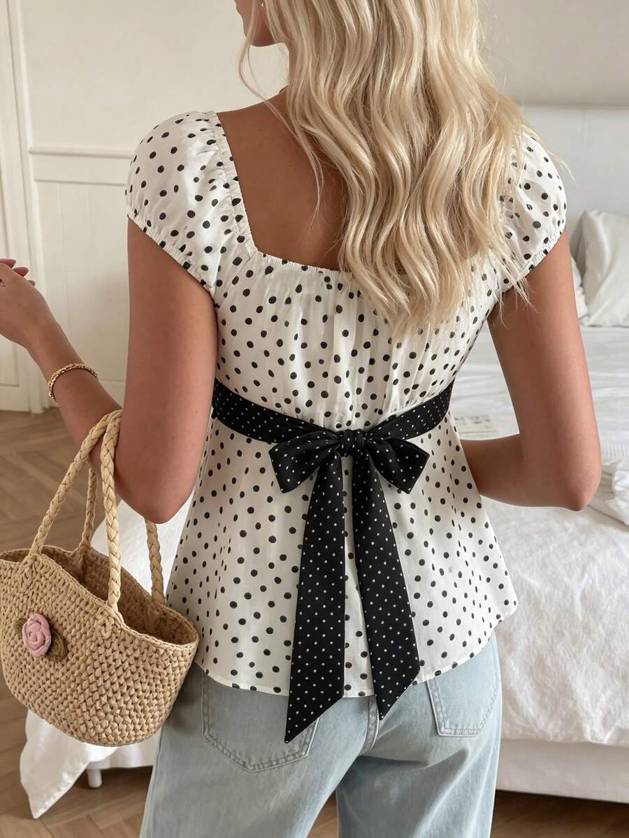 Women's short sleeve square neck polka dot top with ruched detailing, flared hem, and waist tie back.