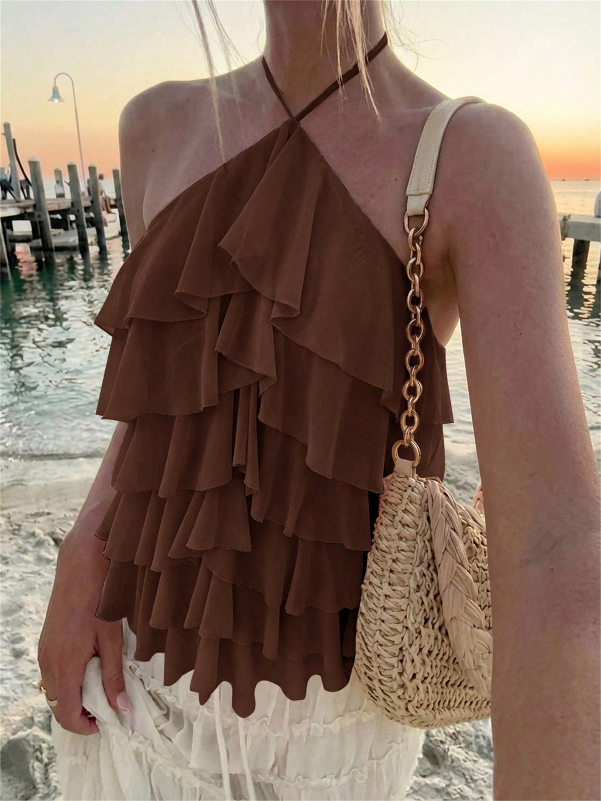 Women's sleeveless halter neck top featuring tiered ruffle layers, a backless cut, and an asymmetrical hem.