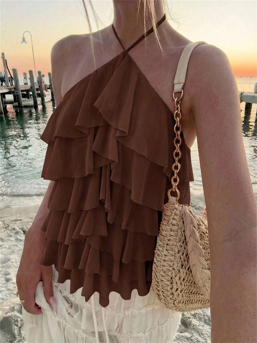 Women's sleeveless halter neck top featuring tiered ruffle layers, a backless cut, and an asymmetrical hem.