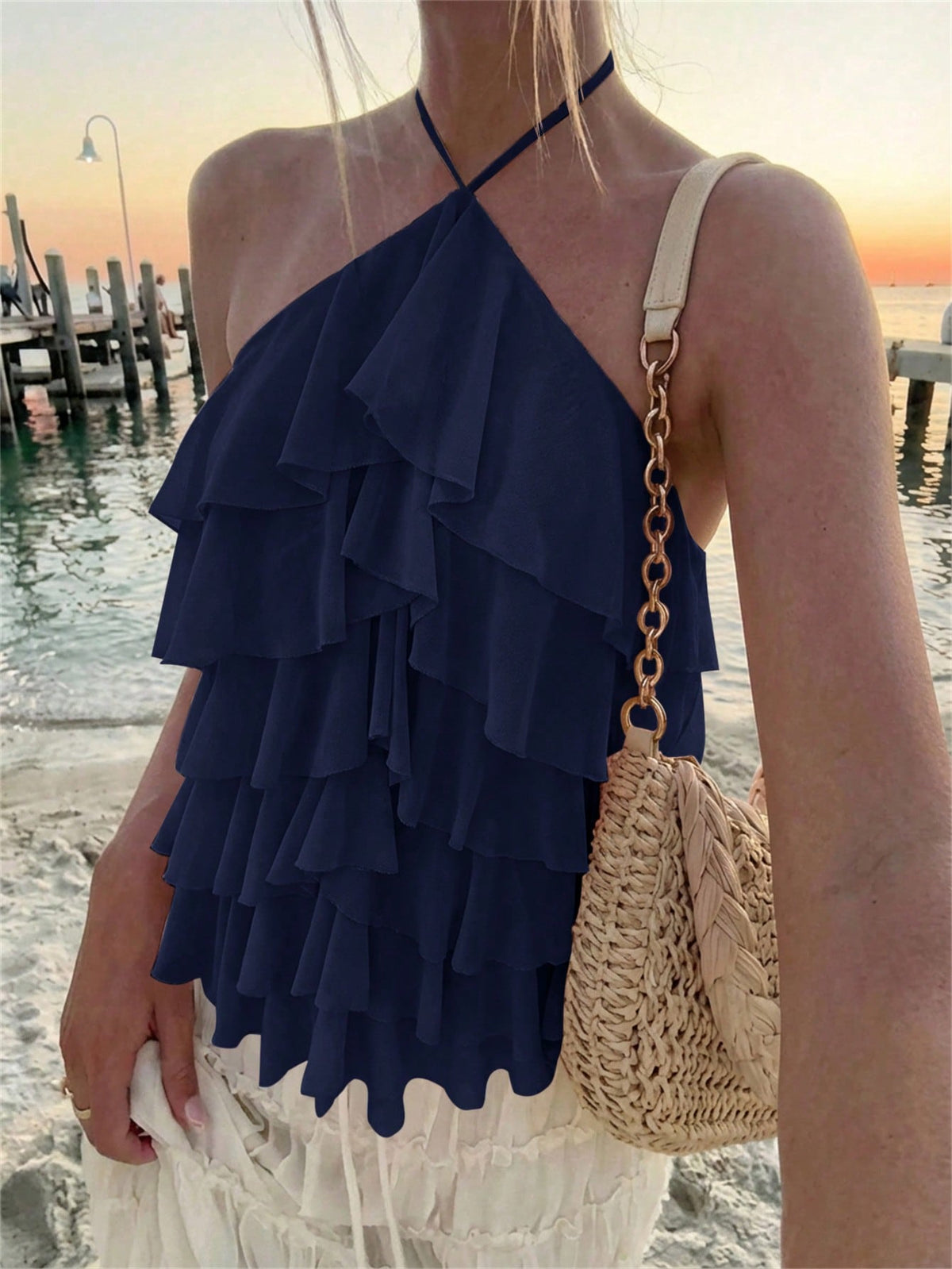 Women's sleeveless halter neck top featuring tiered ruffle layers, a backless cut, and an asymmetrical hem.
