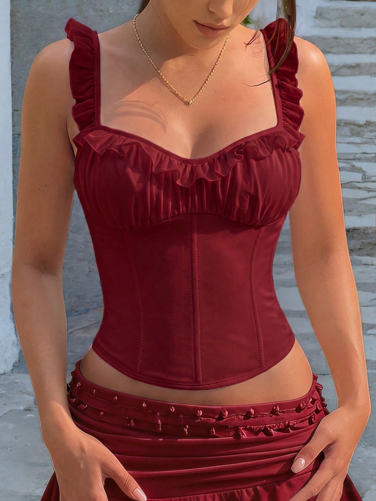 White cropped slim fit camisole top featuring ruffle lettuce trim, lace-up detail, and square neckline.