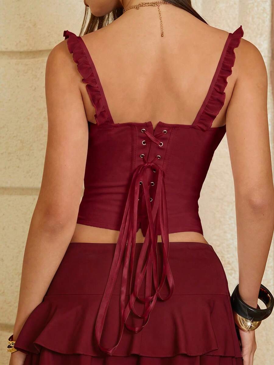 White cropped slim fit camisole top featuring ruffle lettuce trim, lace-up detail, and square neckline.