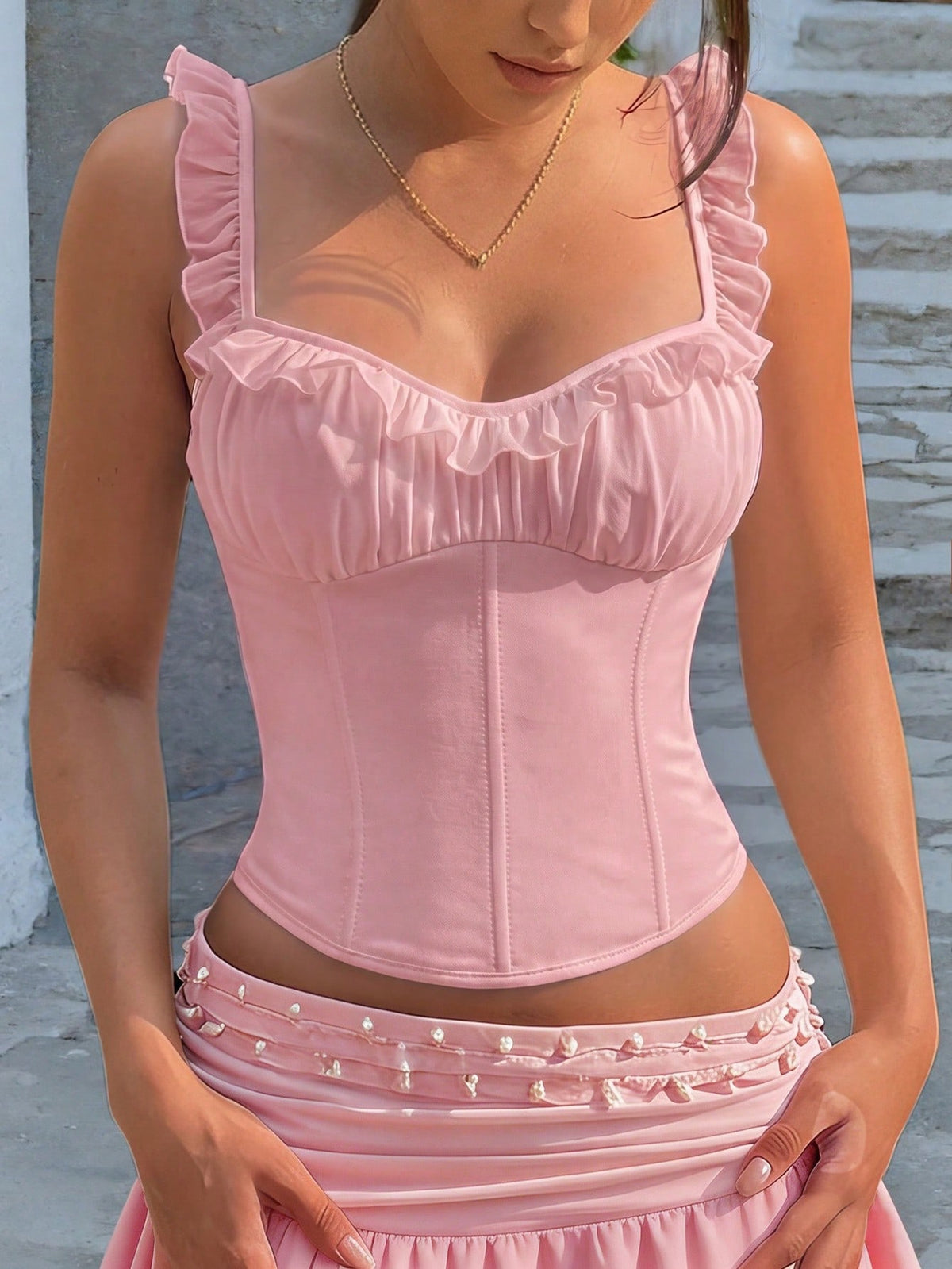 White cropped slim fit camisole top featuring ruffle lettuce trim, lace-up detail, and square neckline.