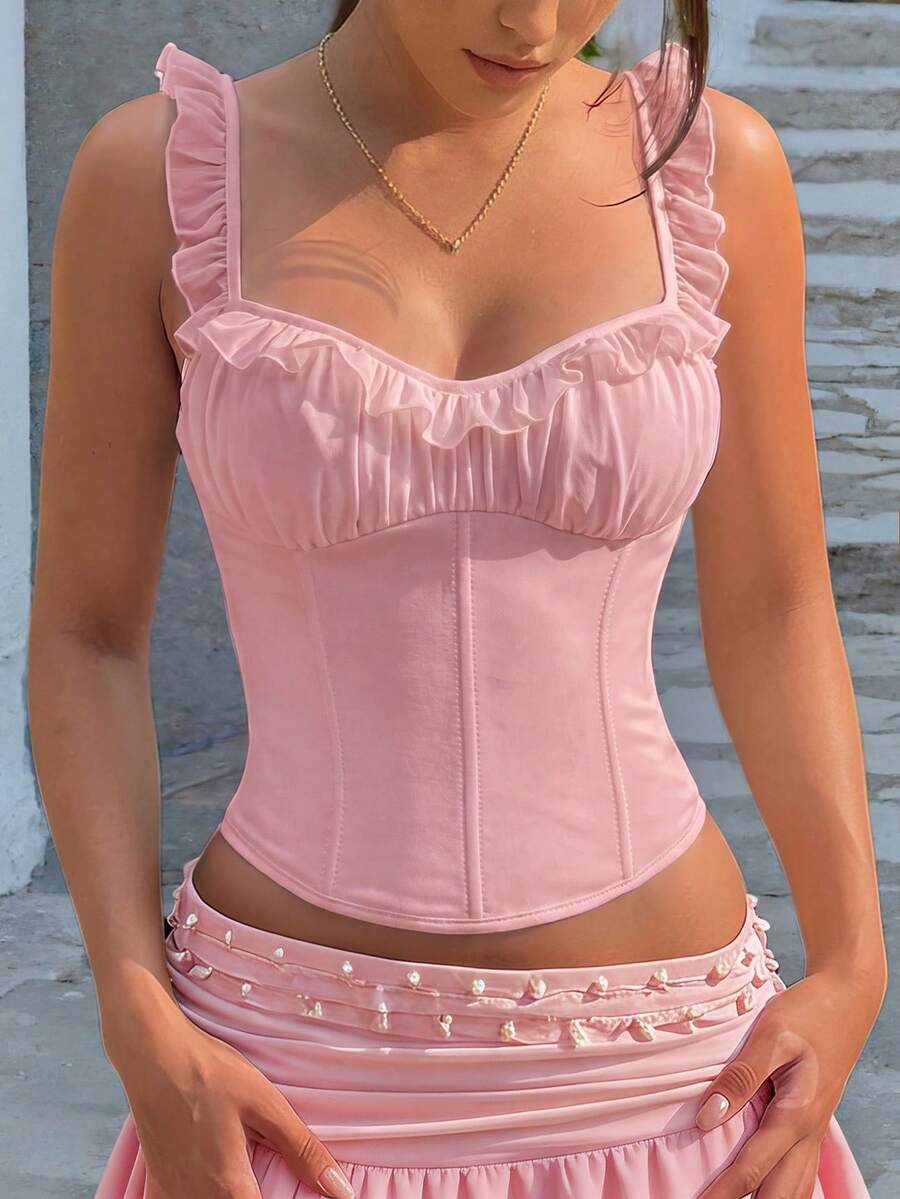 White cropped slim fit camisole top featuring ruffle lettuce trim, lace-up detail, and square neckline.