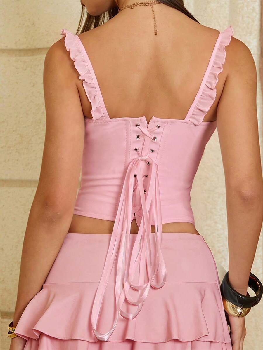 White cropped slim fit camisole top featuring ruffle lettuce trim, lace-up detail, and square neckline.