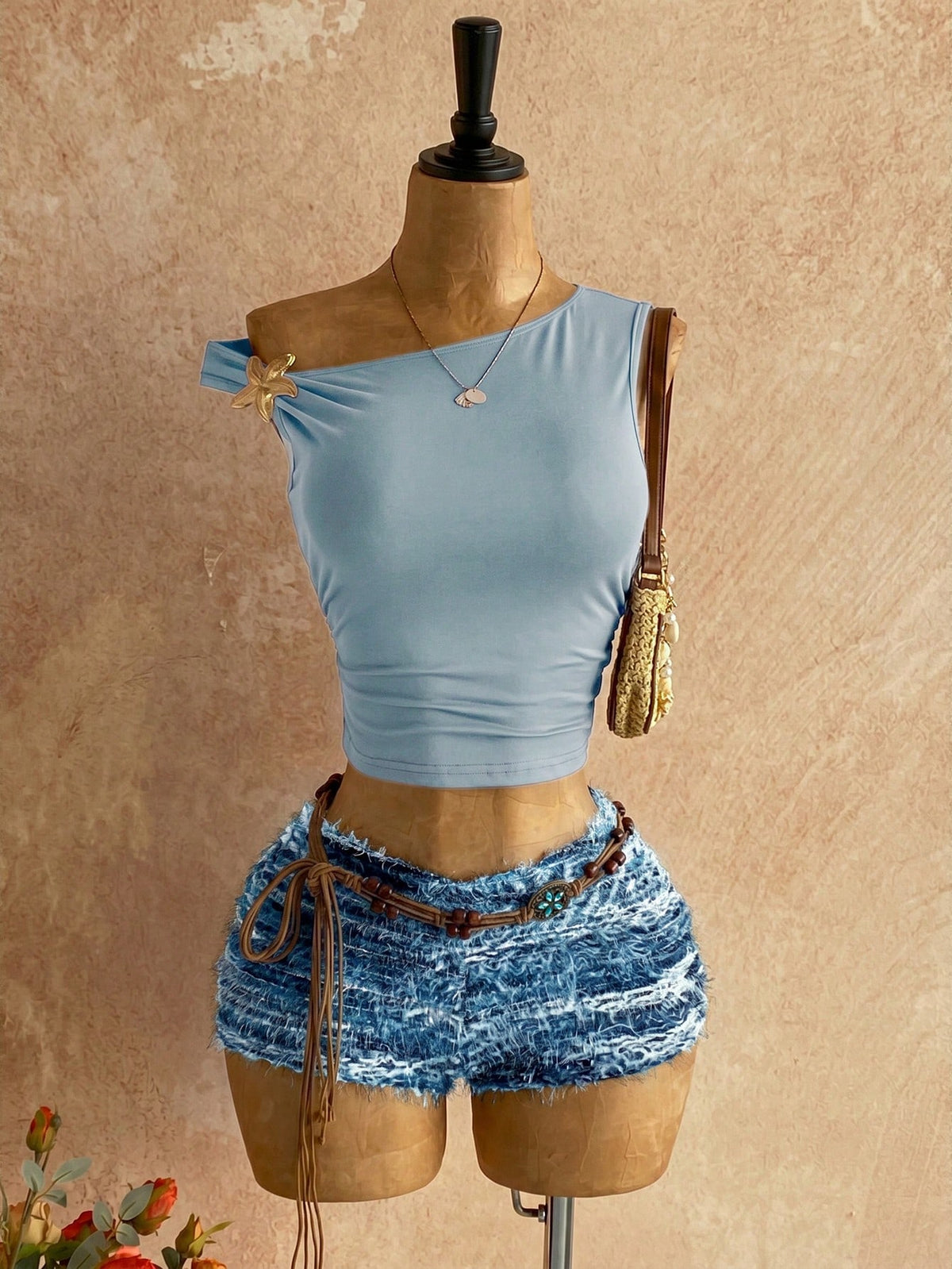 Women's black fuzzy knit two-piece set with an asymmetrical crop camisole top featuring ruched detail and cutout back, paired with matching mini shorts.