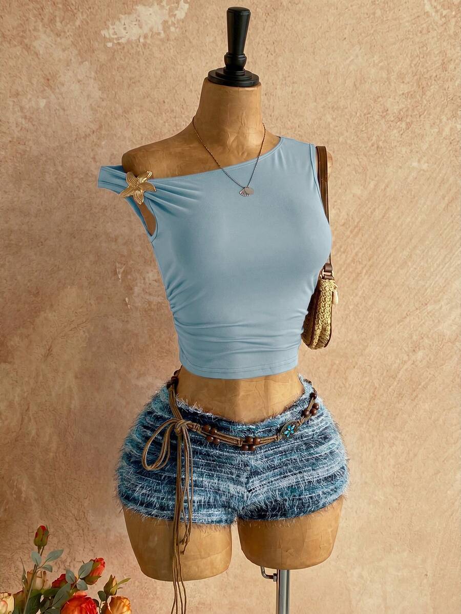 Women's black fuzzy knit two-piece set with an asymmetrical crop camisole top featuring ruched detail and cutout back, paired with matching mini shorts.