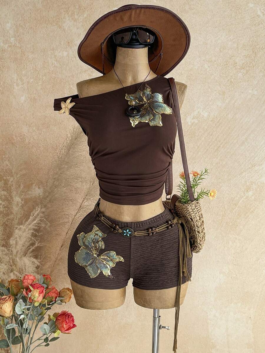 Women's black fuzzy knit two-piece set with an asymmetrical crop camisole top featuring ruched detail and cutout back, paired with matching mini shorts.
