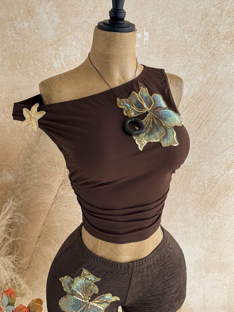 Women's black fuzzy knit two-piece set with an asymmetrical crop camisole top featuring ruched detail and cutout back, paired with matching mini shorts.