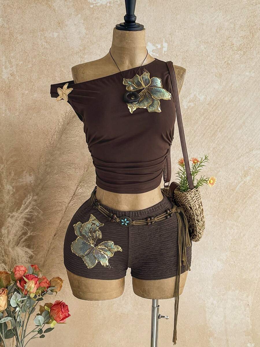 Women's black fuzzy knit two-piece set with an asymmetrical crop camisole top featuring ruched detail and cutout back, paired with matching mini shorts.
