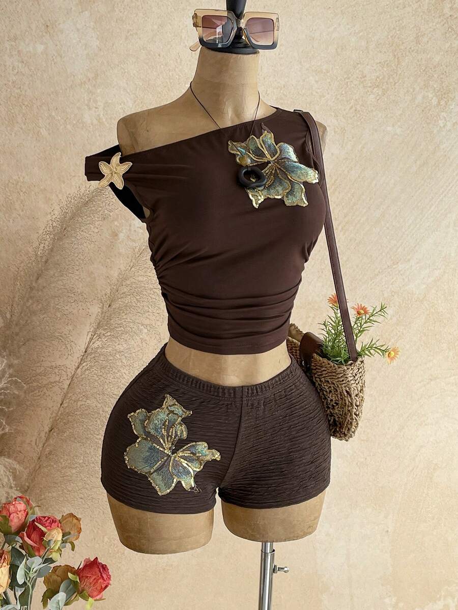 Women's black fuzzy knit two-piece set with an asymmetrical crop camisole top featuring ruched detail and cutout back, paired with matching mini shorts.