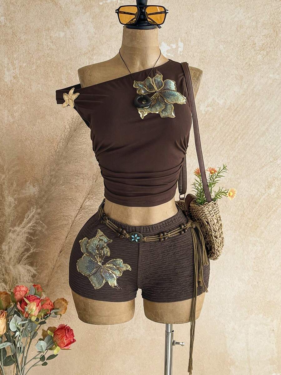 Women's black fuzzy knit two-piece set with an asymmetrical crop camisole top featuring ruched detail and cutout back, paired with matching mini shorts.