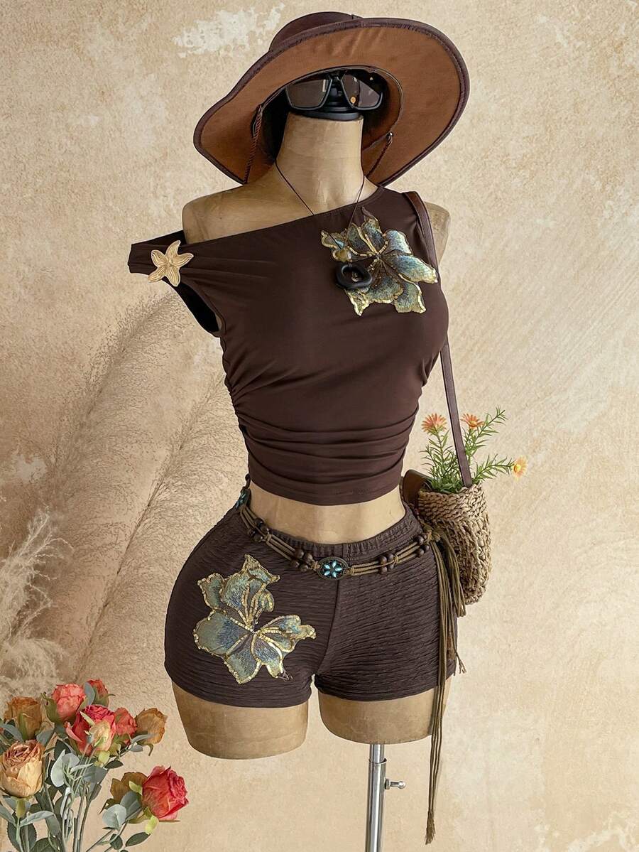 Women's black fuzzy knit two-piece set with an asymmetrical crop camisole top featuring ruched detail and cutout back, paired with matching mini shorts.
