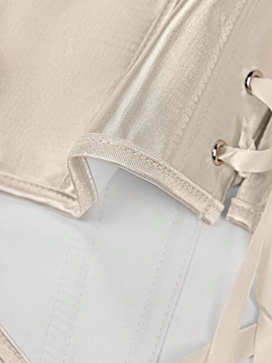 Champagne satin lace camisole crop top featuring spaghetti straps, gold front buttons, boned cup details, and a tie-back design.