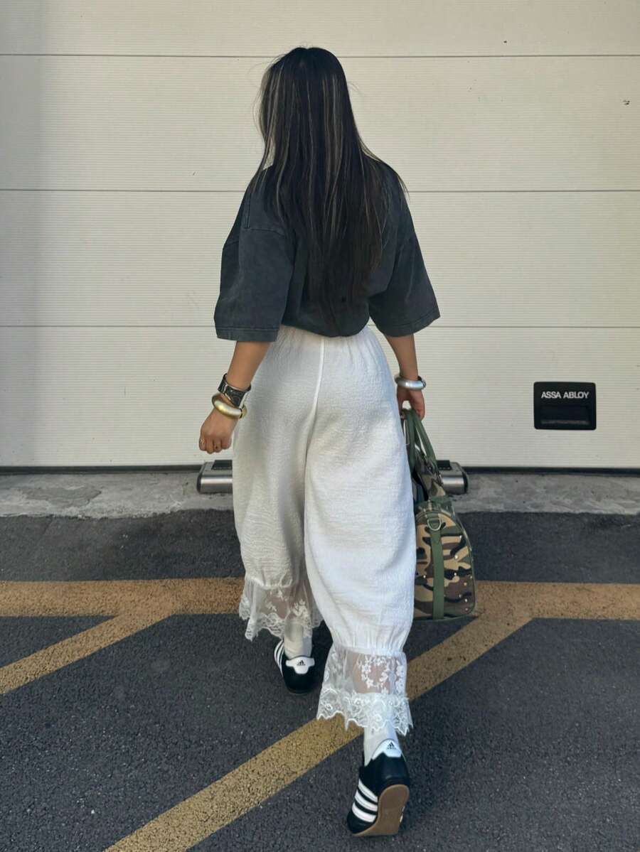 Women's loose-fitting lantern bloomer pants in capri length featuring delicate contrast lace trim and a drawstring waist.