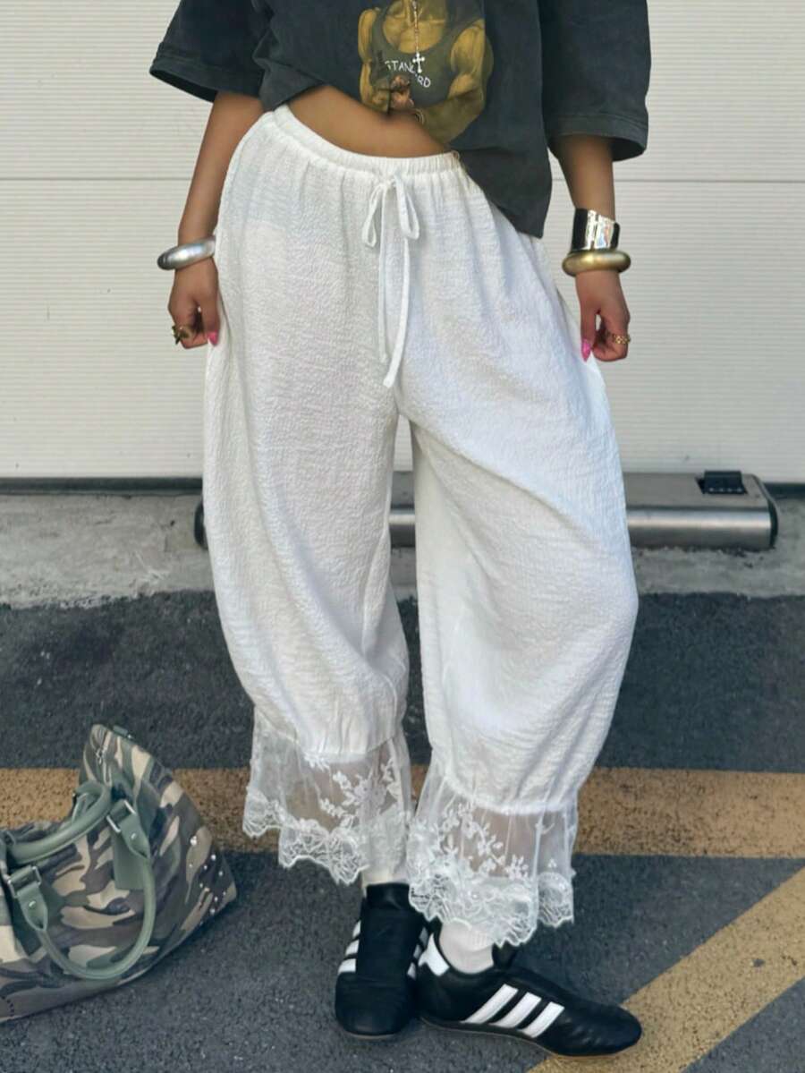 Women's loose-fitting lantern bloomer pants in capri length featuring delicate contrast lace trim and a drawstring waist.