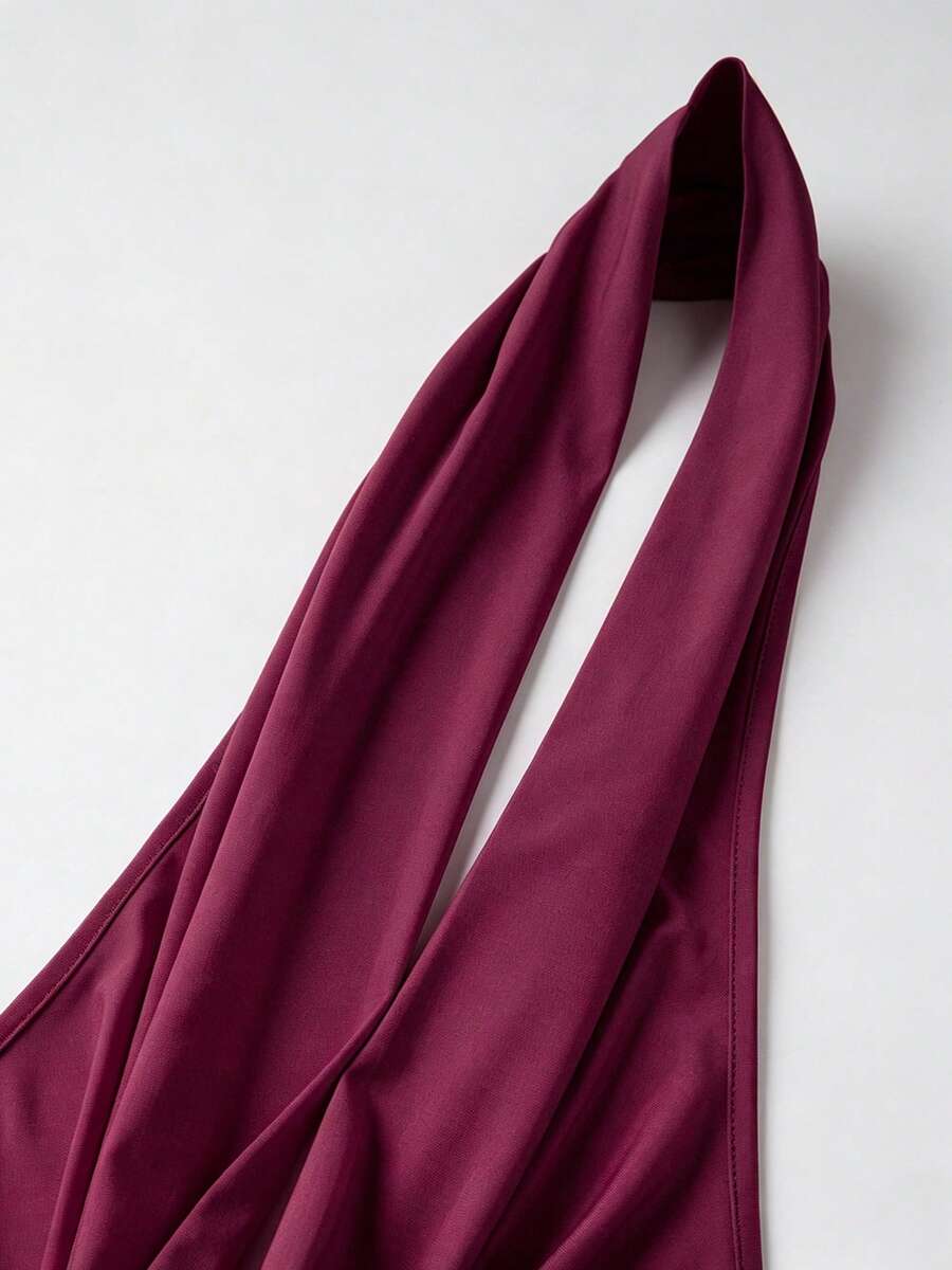 Women's backless halter crop top featuring a draped cowl front, knot detail, and slim fit design.
