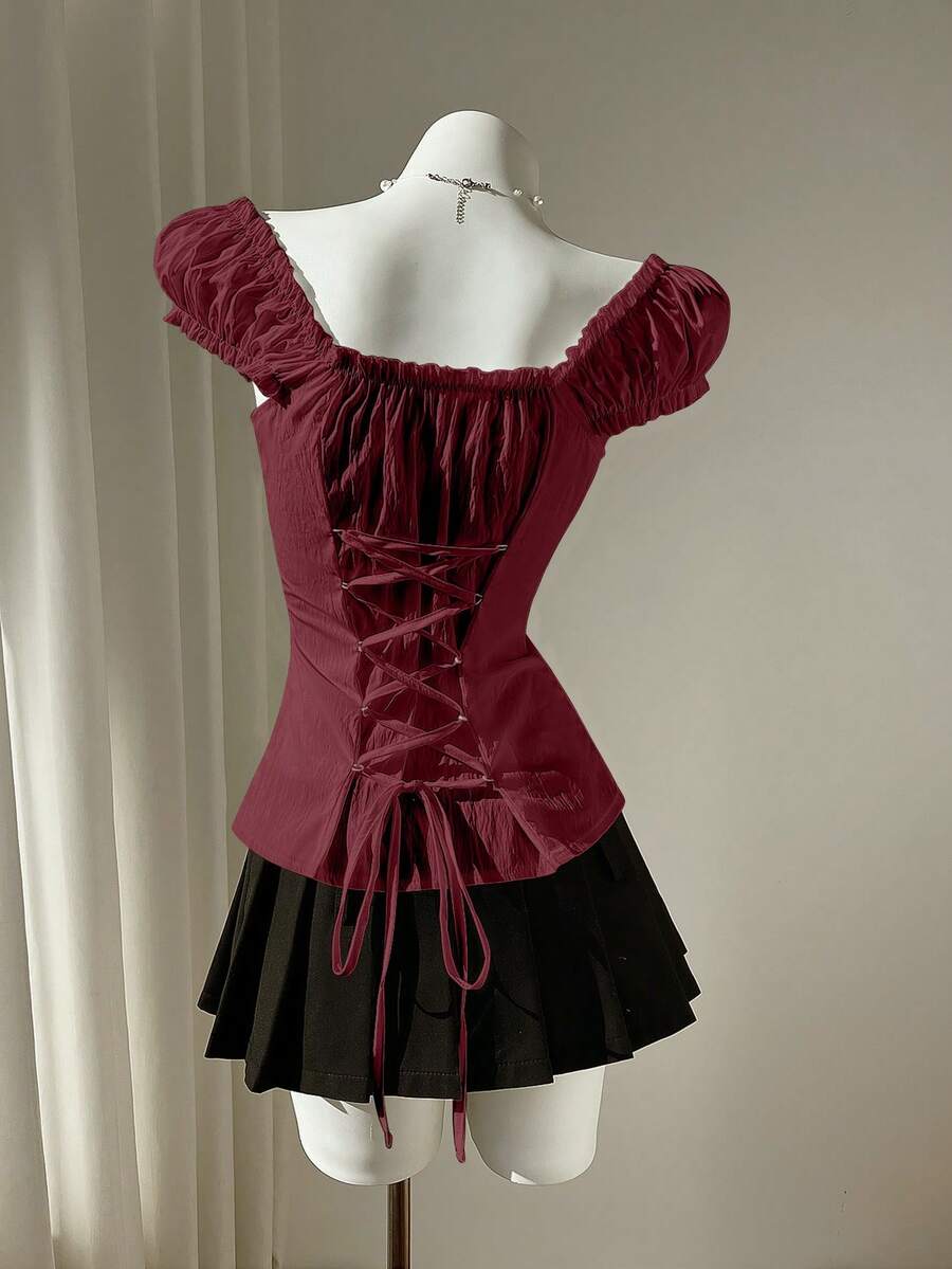 Women's black off-shoulder cap sleeve blouse with ruffled detailing and a tie-back design.