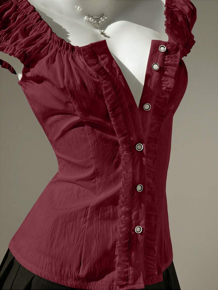 Women's black off-shoulder cap sleeve blouse with ruffled detailing and a tie-back design.