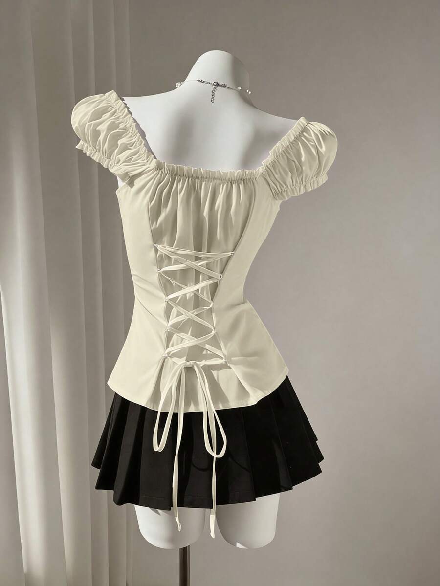 Women's black off-shoulder cap sleeve blouse with ruffled detailing and a tie-back design.