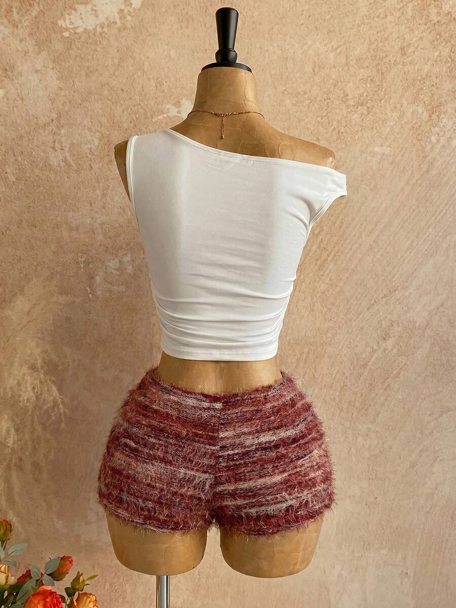 Women's black fuzzy knit two-piece set with an asymmetrical crop camisole top featuring ruched detail and cutout back, paired with matching mini shorts.