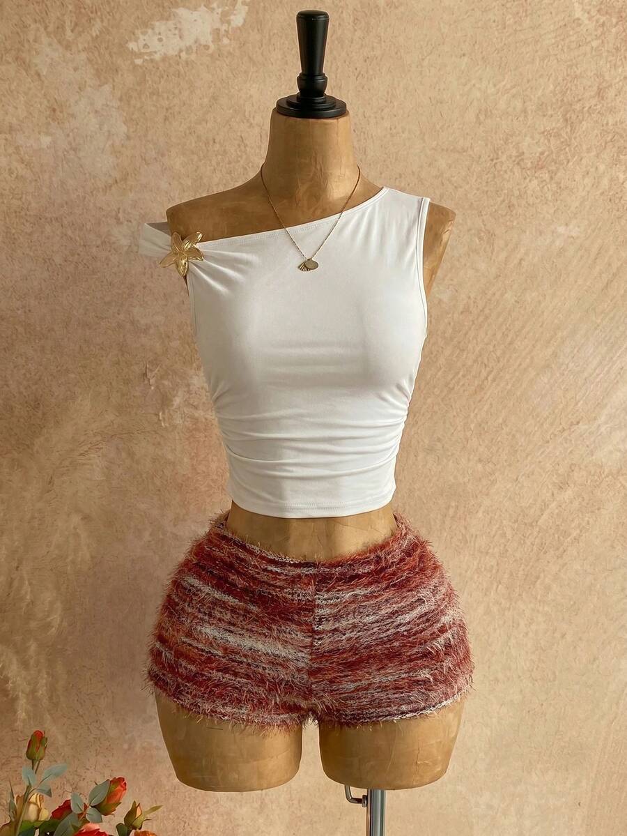 Women's black fuzzy knit two-piece set with an asymmetrical crop camisole top featuring ruched detail and cutout back, paired with matching mini shorts.