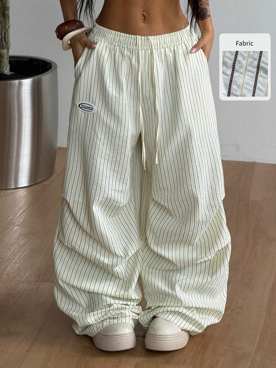 Women's black and white striped wide leg pants featuring an elastic drawstring waistband, side pockets, and a loose straight leg fit.