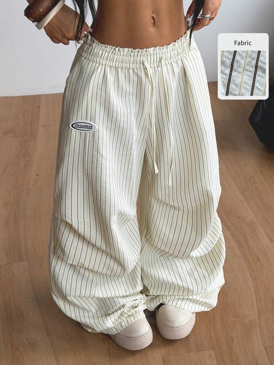 Women's black and white striped wide leg pants featuring an elastic drawstring waistband, side pockets, and a loose straight leg fit.