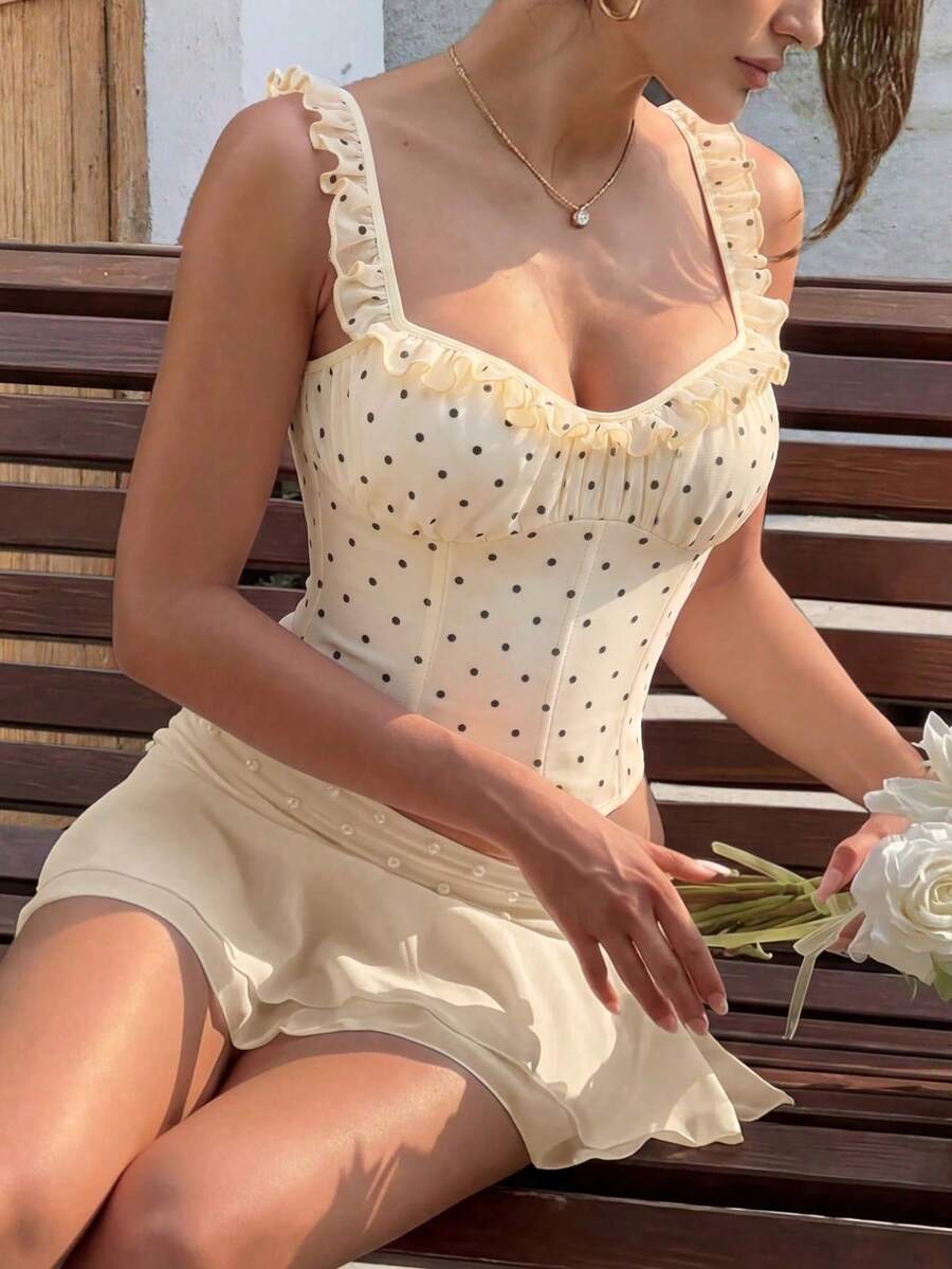 White cropped slim fit camisole top featuring ruffle lettuce trim, lace-up detail, and square neckline.