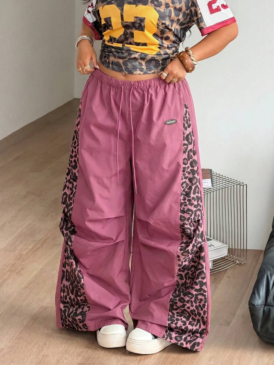 Women's high waist wide leg pants in black featuring leopard print patchwork details and an elastic drawstring waistband.