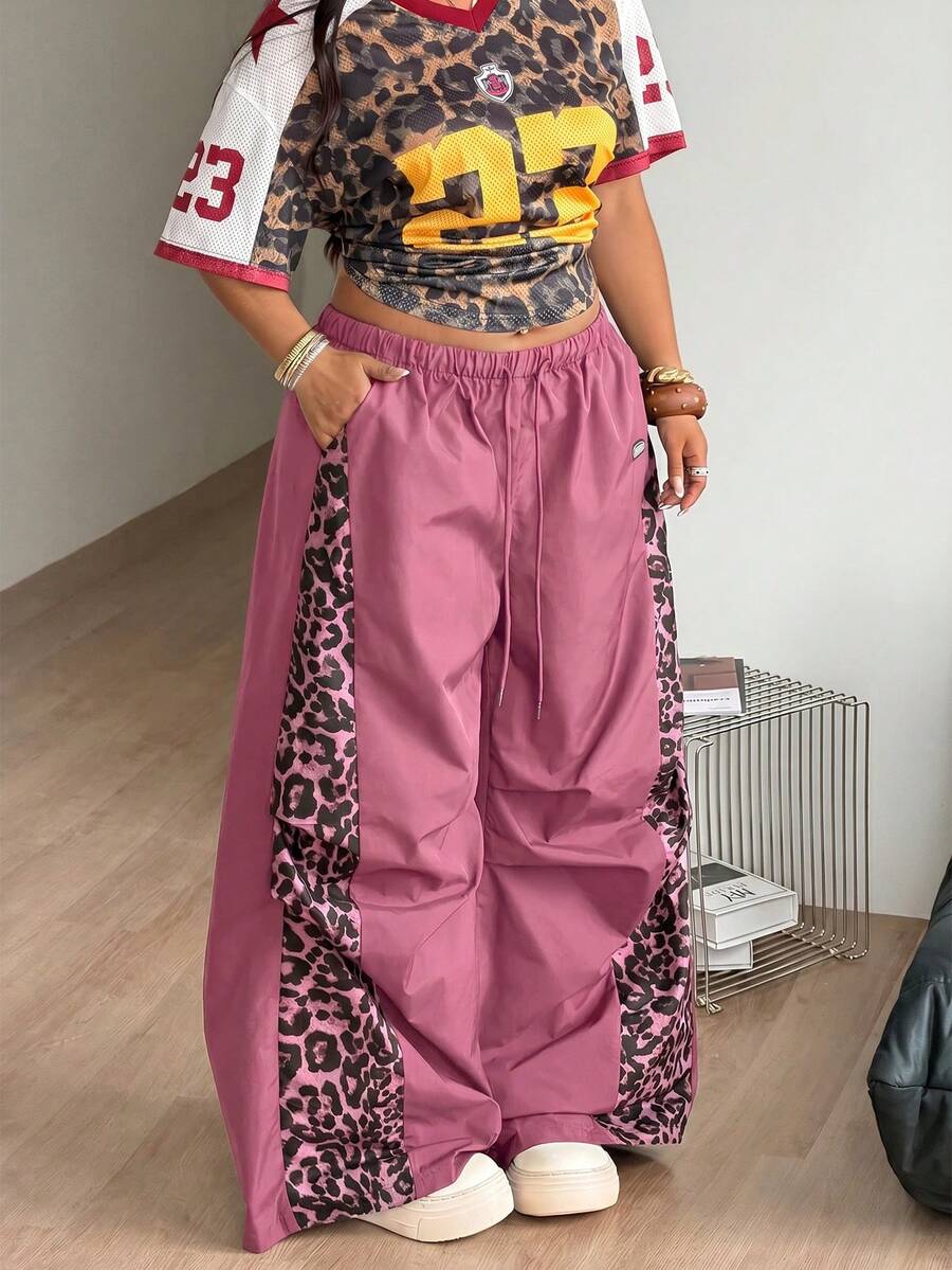 Women's high waist wide leg pants in black featuring leopard print patchwork details and an elastic drawstring waistband.