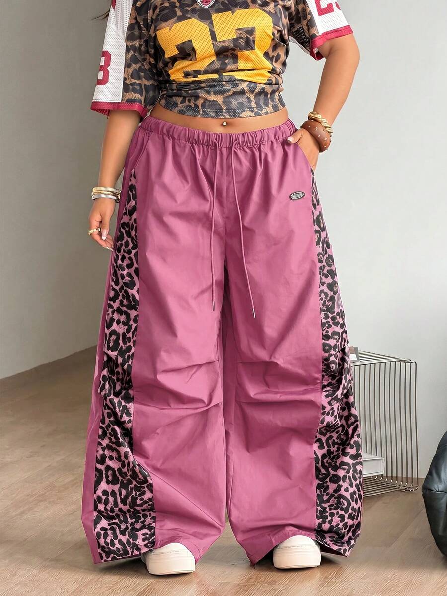 Women's high waist wide leg pants in black featuring leopard print patchwork details and an elastic drawstring waistband.
