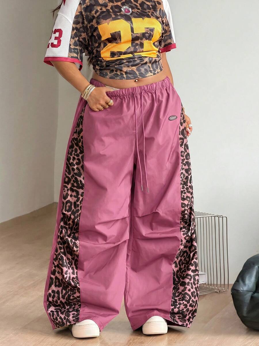 Women's high waist wide leg pants in black featuring leopard print patchwork details and an elastic drawstring waistband.