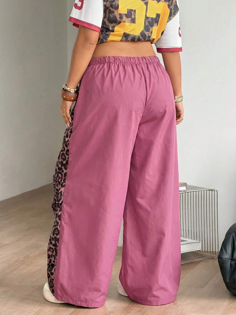 Women's high waist wide leg pants in black featuring leopard print patchwork details and an elastic drawstring waistband.