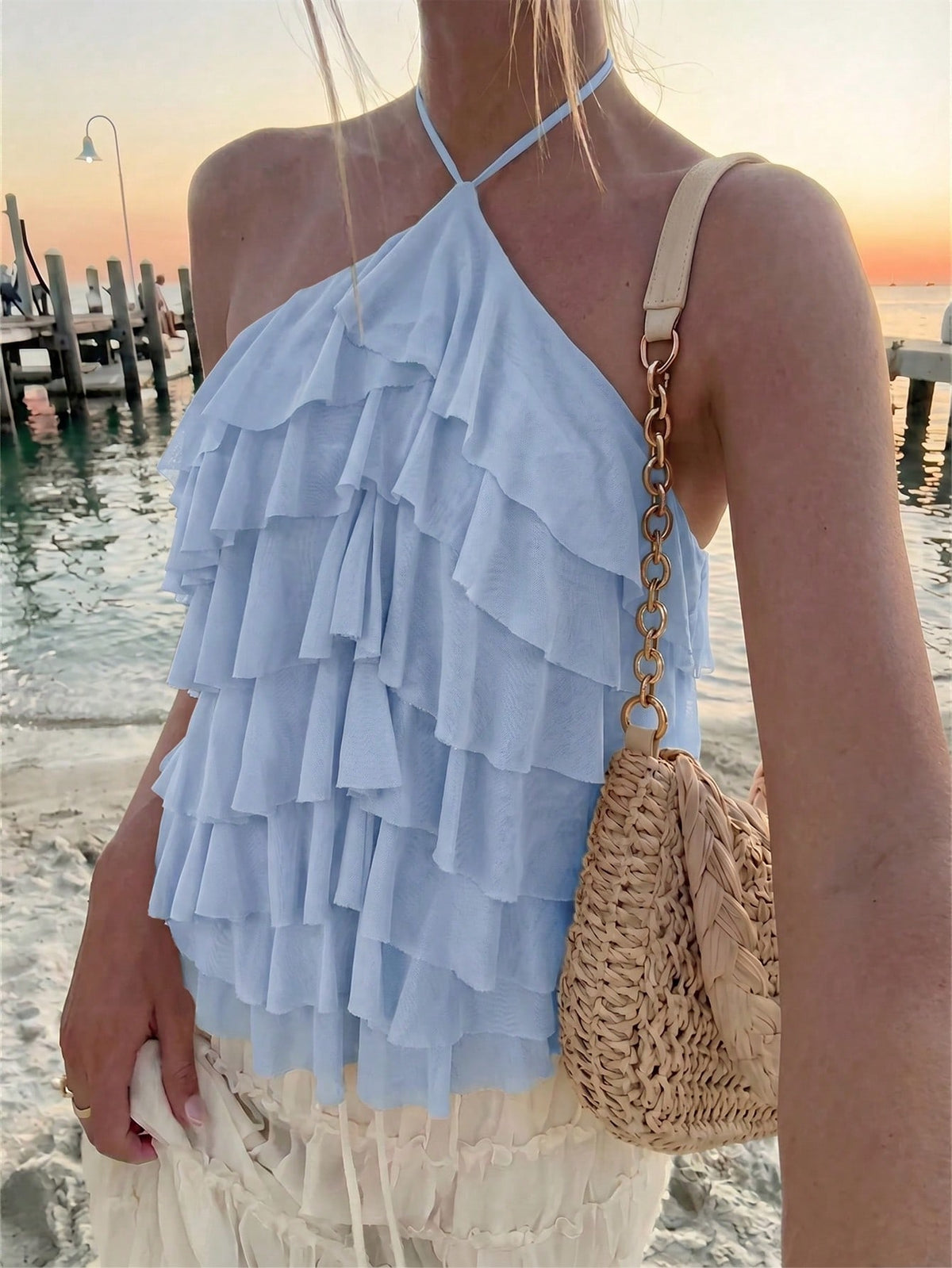Women's sleeveless halter neck top featuring tiered ruffle layers, a backless cut, and an asymmetrical hem.