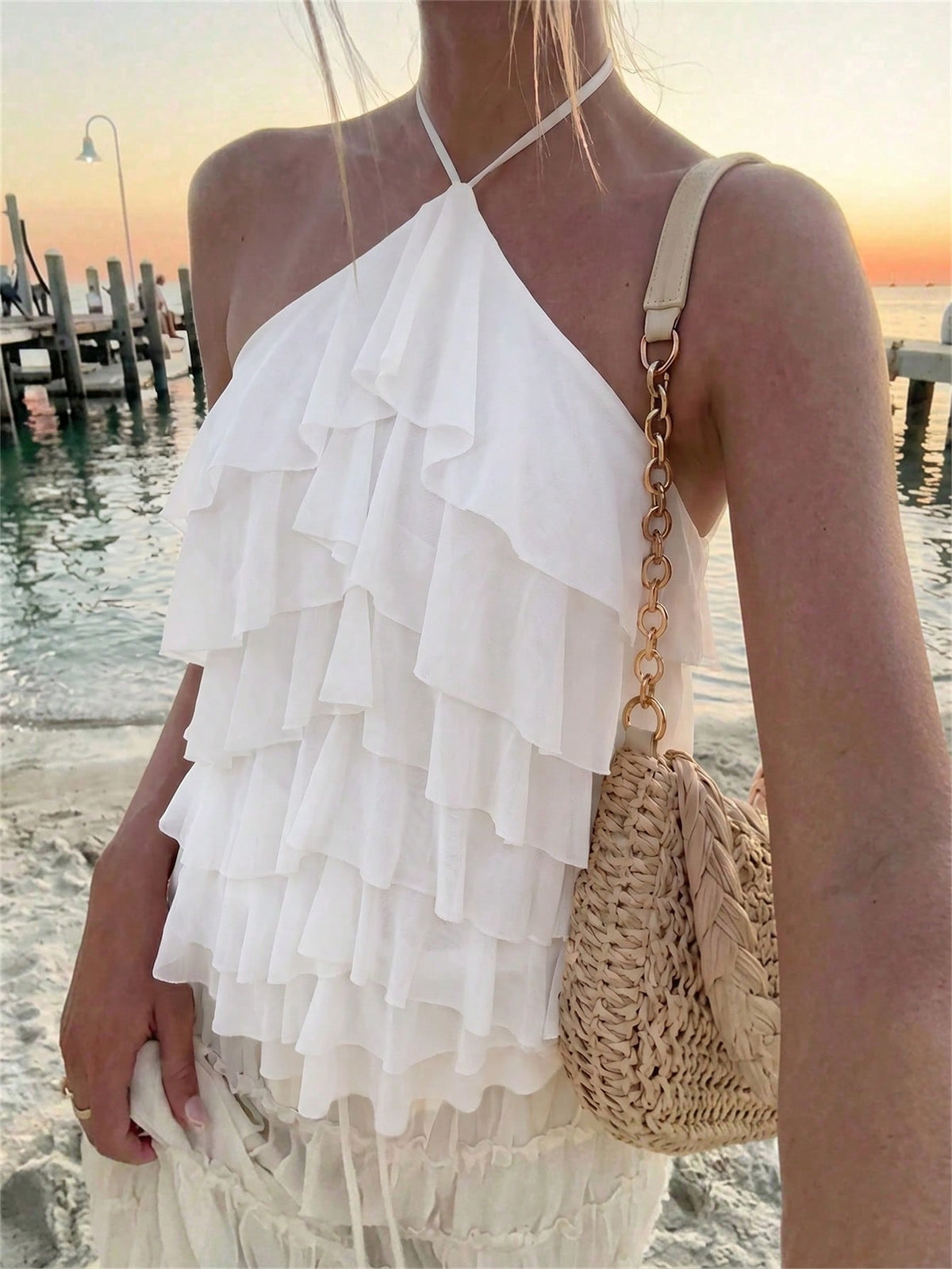 Women's sleeveless halter neck top featuring tiered ruffle layers, a backless cut, and an asymmetrical hem.