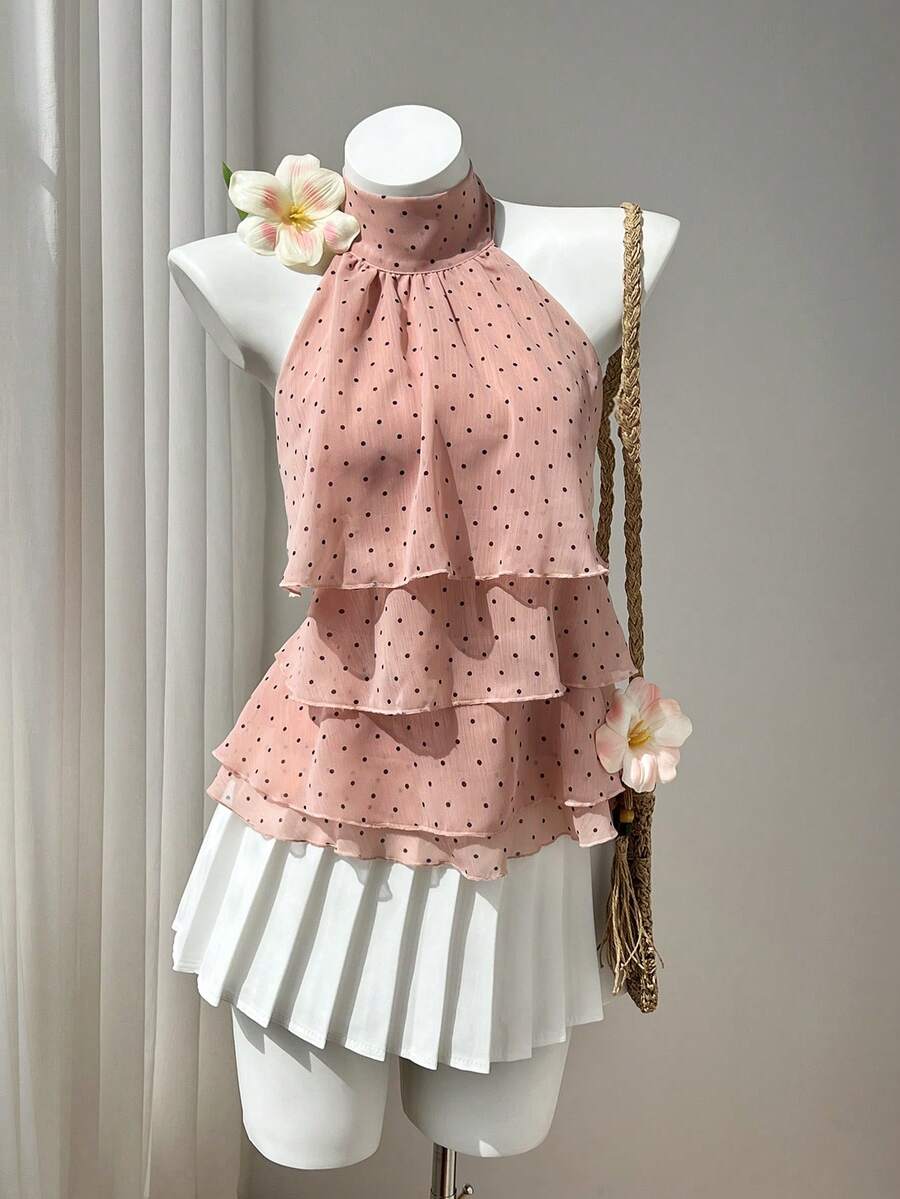Women's white sleeveless halter neck top featuring pleated fabric, backless tie strap design, and a flared layered ruffle hem.