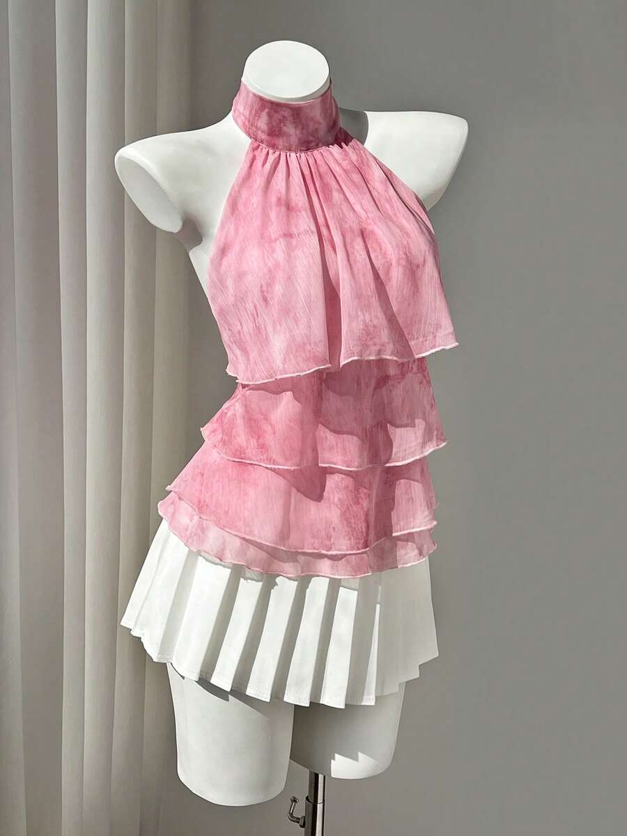 Women's white sleeveless halter neck top featuring pleated fabric, backless tie strap design, and a flared layered ruffle hem.