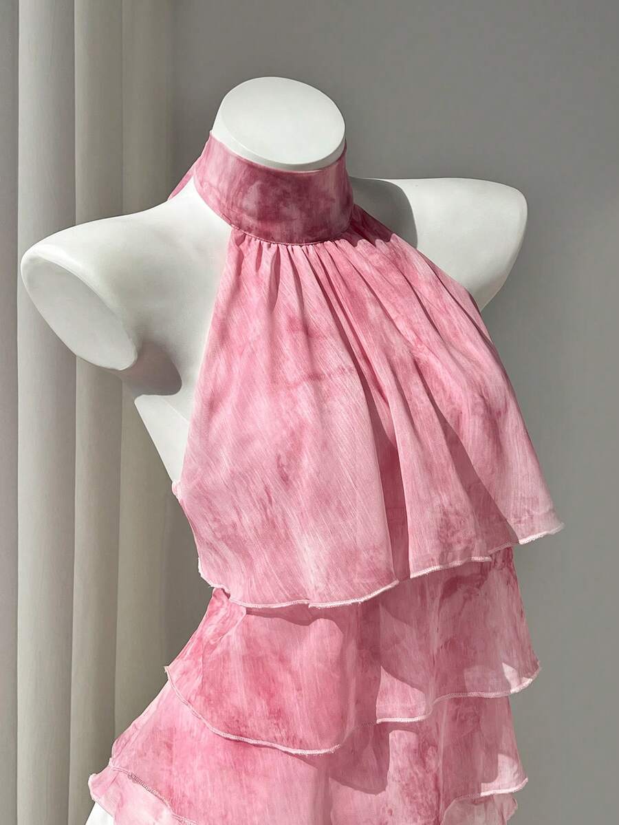 Women's white sleeveless halter neck top featuring pleated fabric, backless tie strap design, and a flared layered ruffle hem.