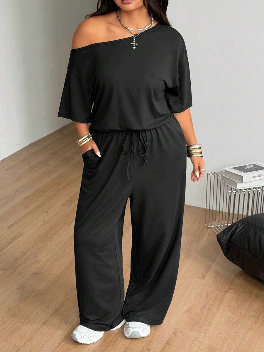 Plus size women's wide leg jumpsuit in dark grey featuring an asymmetrical neckline, short batwing sleeves, and a drawstring high waist with side pockets.
