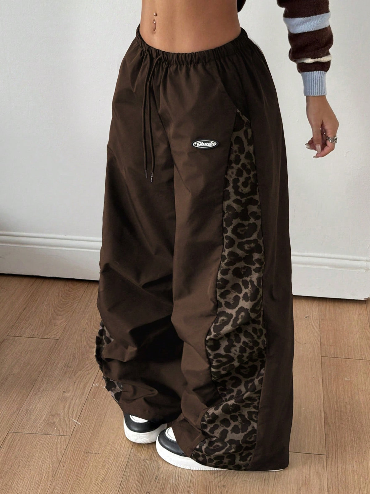 Women's high waist wide leg pants in black featuring leopard print patchwork details and an elastic drawstring waistband.