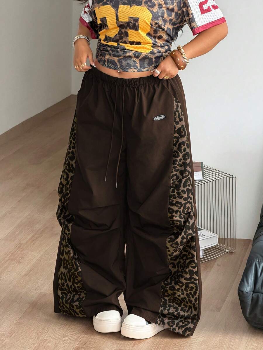 Women's high waist wide leg pants in black featuring leopard print patchwork details and an elastic drawstring waistband.